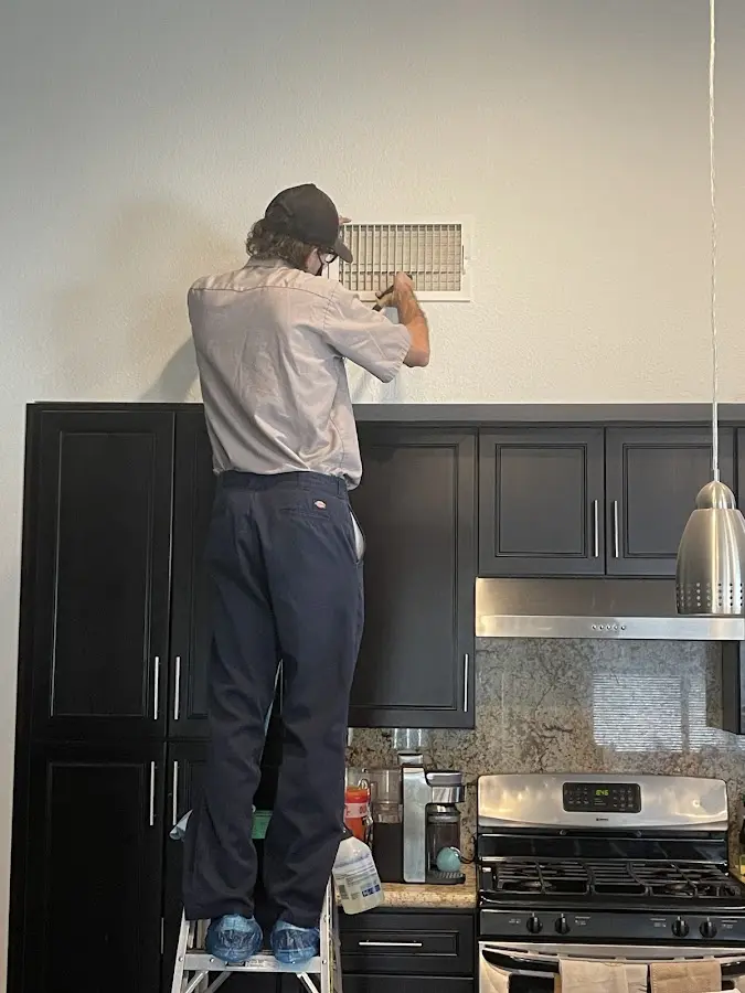 Technician inspecting an air vent during HVAC service in Vancouver